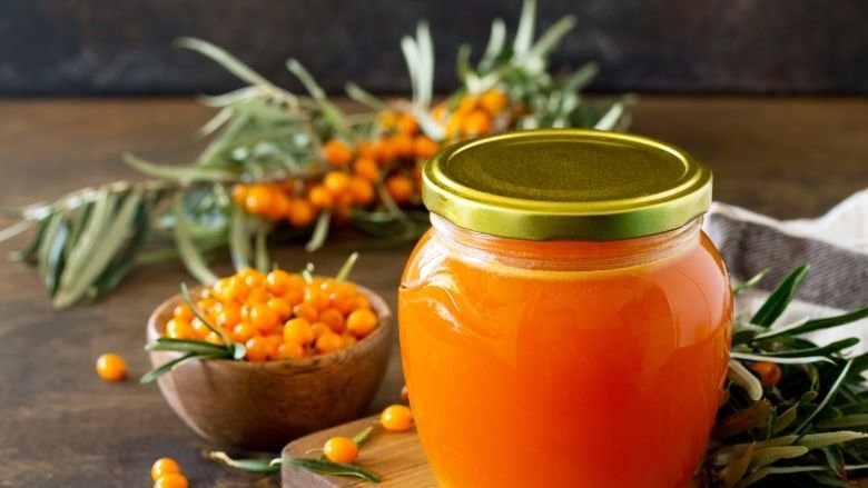 Orange sea buckthorn berries and orange jam on a wooden table